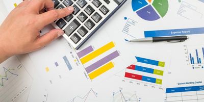Foto de calculadora em cima de papéis com gráficos impressos.