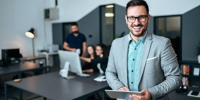 Executivo em sala de reunião segurando um Tablet e sorrindo